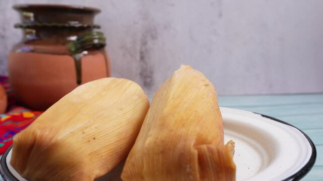 Tamales, comida mexicana, de fondo olla de barro.