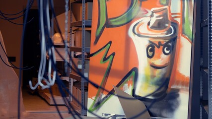 Empty pizza boxes in defective abandoned warehouse with graffiti drawings on walls, tilt up shot....