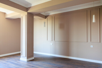 A large empty room with a white wall and a brown pillar
