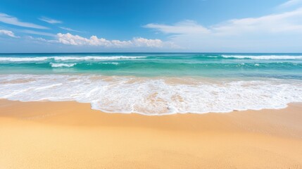 Fototapeta premium The beach features soft golden sand and calm ocean waves under a bright blue sky, inviting relaxation and enjoyment for all who visit