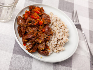 Traditional dish of Russian cuisine is pearl porridge with stewed chicken hearts with vegetables. Served with bread