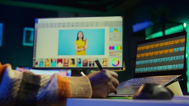 Male graphic artist using essential digital tools on dual monitors, professional design work showcasing modern setup at home. Editor designer showing advanced photo editing skills. Camera B.