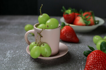 Fresh strawberry and green grape on dark background. Agriculture farm. Healthy eating lifestyle.