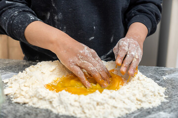 Close-up of young woman's hands mixing eggs and flour on a counter