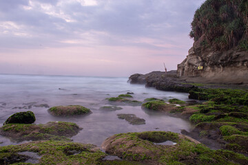 the beautiful view of a tropical beach in the morning, with white sand and coral rocks hit by ocean waves. Landscape images are taken with slow speed technique.