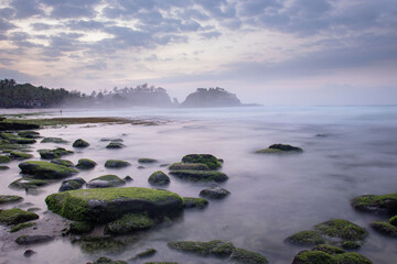 the beautiful view of a tropical beach in the morning, with white sand and coral rocks hit by ocean waves. Landscape images are taken with slow speed technique.