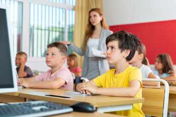 Portrait of diligent schoolboy who writing exercises at lesson in primary school