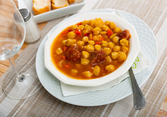 Thick and satisfying stew soup made from pork, beef, poultry, sausages with vegetables and chickpeas