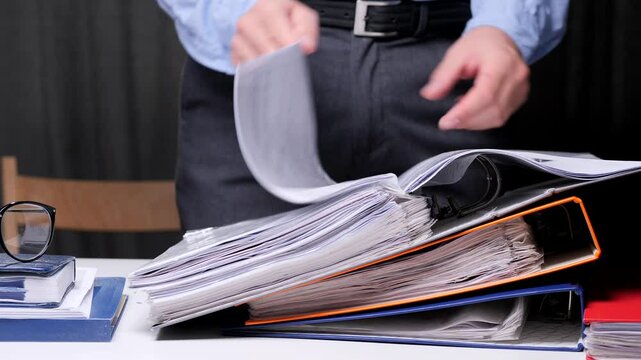 Businessman office worker searching through stack of files and documents