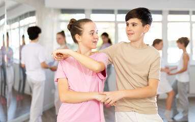 Fototapeta premium Group of teenagers, girls and boys, dance a slow ballroom dance in a choreography studio