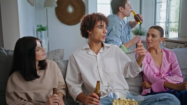 Curly guy talking friends sitting couch at living room. People watching sitcom