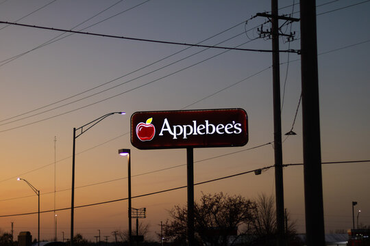 Rockford, Illinois, USA - November 15, 2024: The logo of Applebee's fast food chain restaurant on a big exterior sign with a colorful sunset behind it.