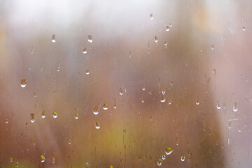 A closeup photo with shallow aperture focusing on rain drops on a glass window.
