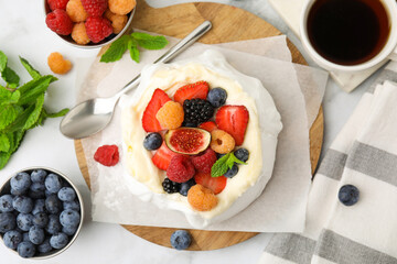 Pavlova cake (meringue dessert) with whipped cream, fresh berries, fig and mint on white marble table, flat lay