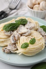 Delicious pasta with mushrooms and basil on table, closeup