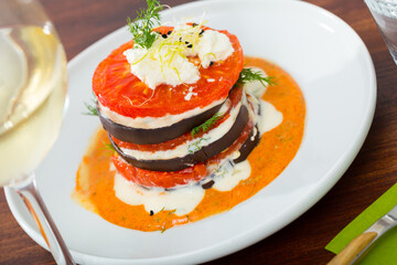 Grilled eggplant and tomatoes tower with spicy garlic sauce and greens