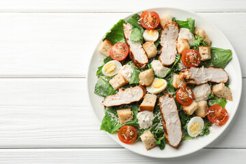 Tasty Caesar salad with chicken and tomatoes on white wooden table, top view. Space for text