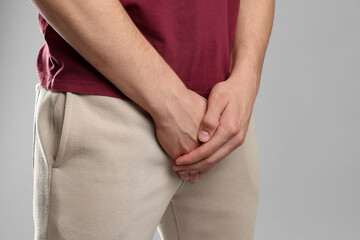 STD (sexually transmitted diseases). Man suffering from symptoms on grey background, closeup