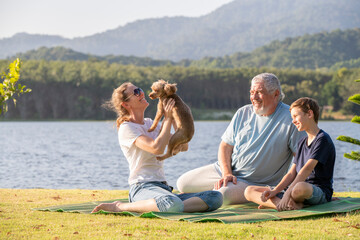 Family share a moment of joy and connection picnic mat, holding up a small playful dog with a delighted expression clearly enjoying the cheerful moment perfect setting for relaxation holidays