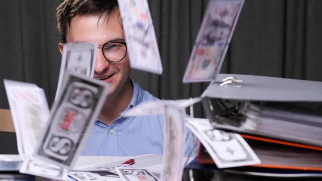 Office worker, businessman throws money from a money gun at the workplace