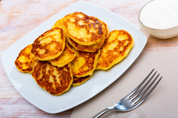 Cottage cheese pancakes on white plate, traditional russian dish Syrniki