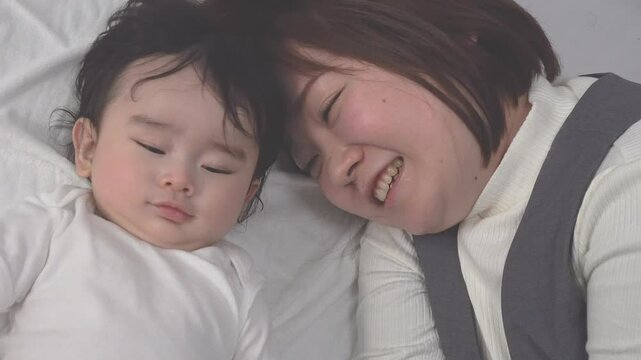 0歳児の赤ちゃんと横になり一緒に遊ぶお母さんのクローズアップの俯瞰、固定撮影