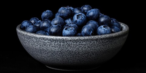 Fresh, juicy blueberries in a bowl against a black background. Low key photography.