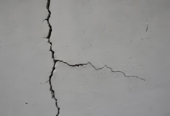 A close-up of a gray cement wall with crack patterns