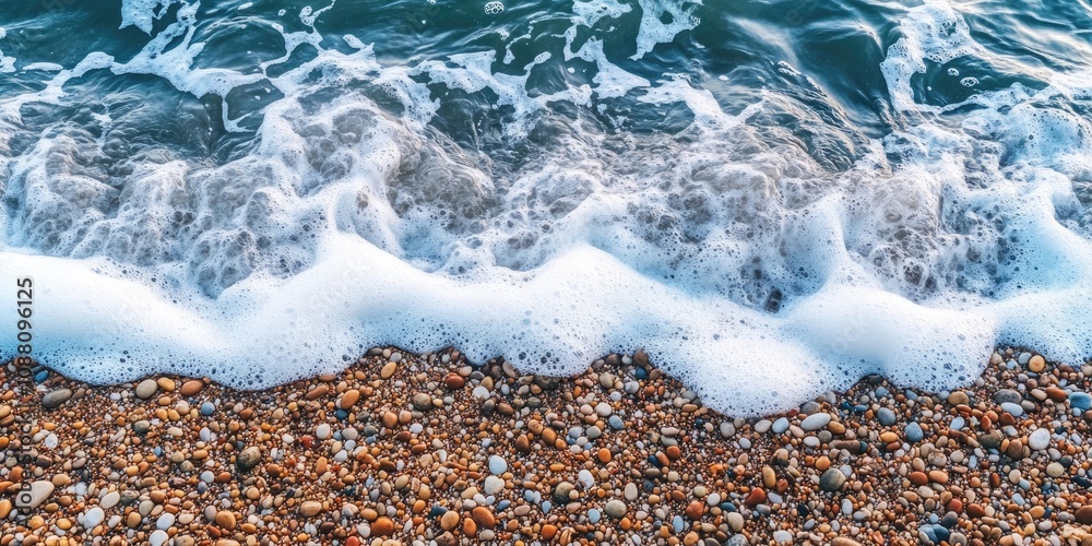 Poster a foaming wave from the sea separates the sand on the seabed from the pebbles on the shore.