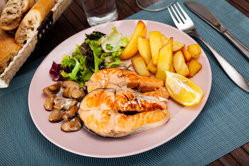 Image of deliciously steak of fried salmon with potatoes and mushrooms on plate