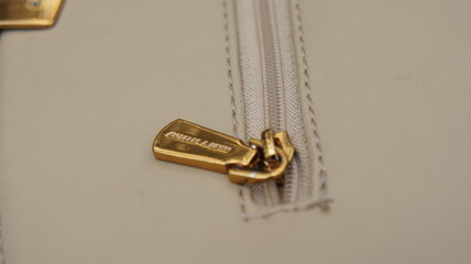 Close-up of a Gold Zipper Pull on a Beige Leather Bag