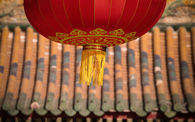 Closeup of hanging red lantern against Chinese traditional rooftop. Beijing, China