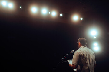 Man with Clipboard Making a Presentation on Stage. Professional educator presenting and explaining his theories 
