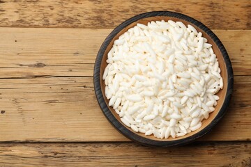 Puffed rice in bowl on wooden table, top view. Space for text