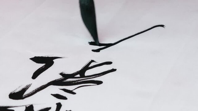 a man is practicing chinese calligraphy using a brush pen on white paper