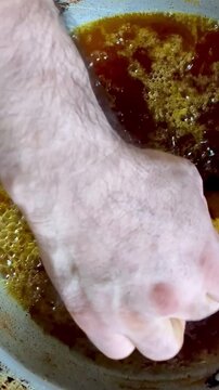 Macro shot shows fish chunks deep‑fried in seasoned oil inside a traditional metal wok, highlighting bubbling texture and crisping surfaces.