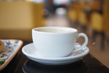 An Elegant White Coffee Cup Placed on a Saucer in a Contemporary Cafe Setting with Style