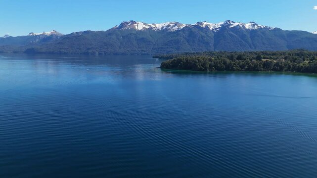 aerial view of Lynch Bay in the Arrayanes Forest, located within Nahuel Huapi Lake in Patagonia, Argentina. The pristine blue waters contrast with the lush green forest, creating a serene and pictures