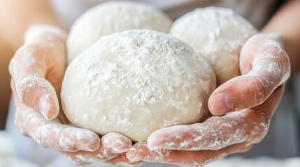 Hands holding three dough balls covered in flour