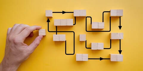 Connecting the Dots: A hand carefully places a wooden block into a complex flowchart, symbolizing a strategic approach to problem-solving and process optimization.  
