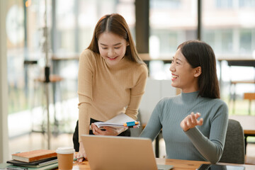 Two Asian businesswomen working with documents in an office.