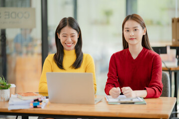 Obraz premium Two Asian businesswomen working with documents in an office.