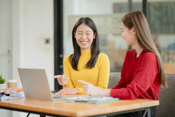 Two Asian businesswomen working with documents in an office.