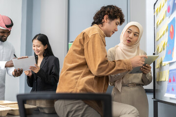 Two business colleagues working together on project planning, analyzing data chart and sticky notes on board, team collaboration, office brainstorming session, diverse professionals in business attire