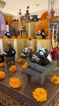 Vibrant Day of the Dead altar with black skulls, candles, marigolds, and traditional stone tools