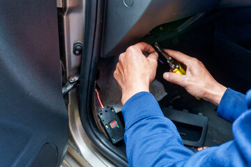 Close-up of a man installing an electronic satellite positioning device in a car. The man is...