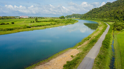 Obraz premium Breathtaking aerial drone view of waterway canal near green paddy crops land at Kampung Wai, Perlis, Malaysia