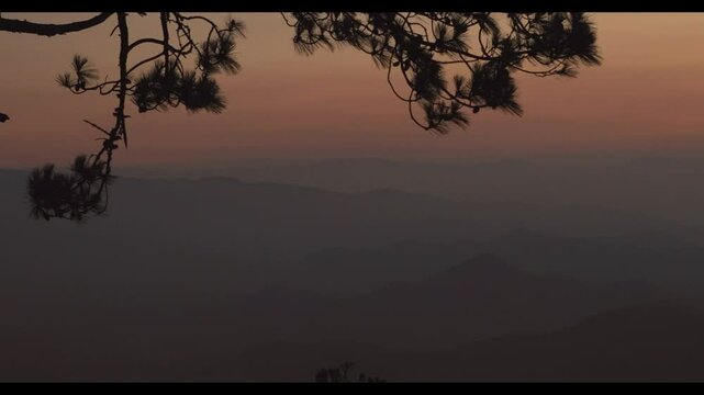 A sunset behind the mountain ridges, taken from the top of a mountain, with shades of purple