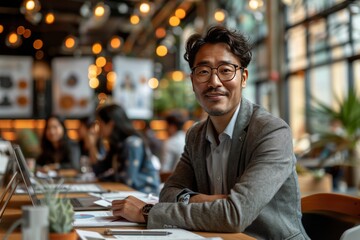 Fototapeta premium Asian manager sitting at the table and communicating with clients via video conference