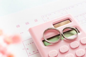 婚姻届と計算機と結婚指輪　結婚資金のイメージ写真